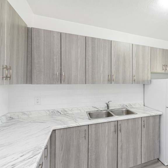 a kitchen with a white refrigerator and grey cabinets.