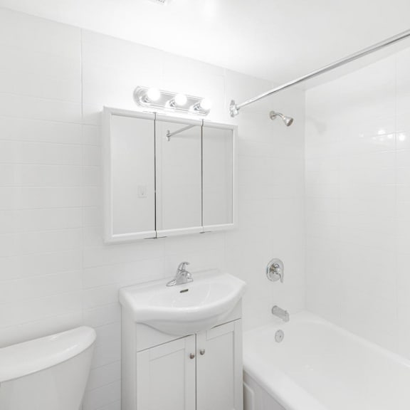a white bathroom with a sink, toilet, and bathtub.