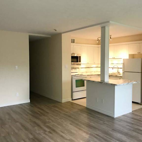 a kitchen with a white island and wooden floors.