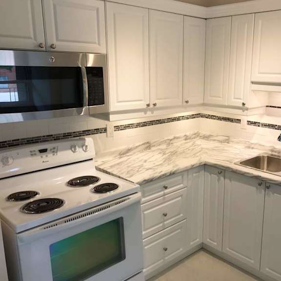 a kitchen with white cabinets and a marble countertop.