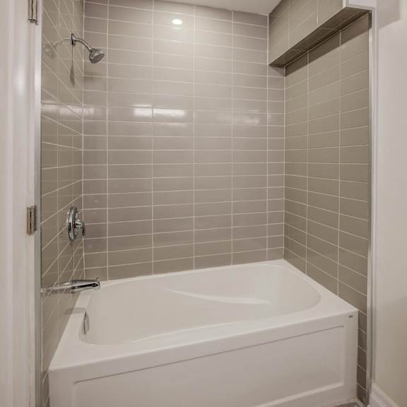 a white bathtub with a shower head and a white toilet in a bathroom.