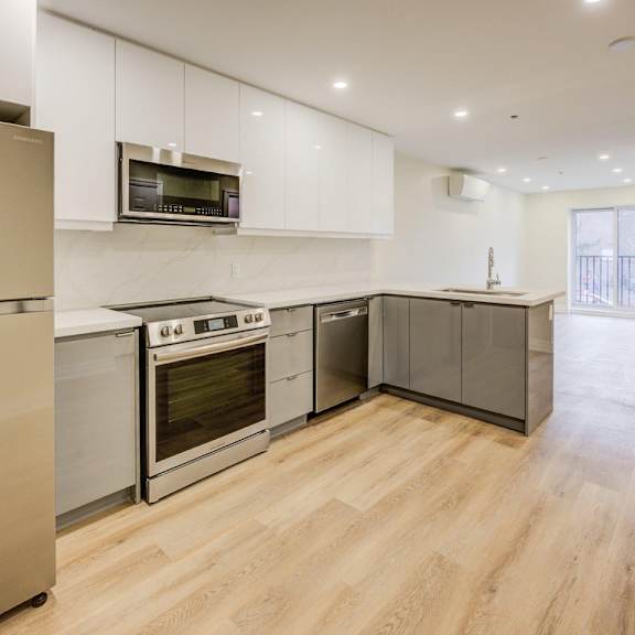 a modern kitchen with stainless steel appliances and wooden flooring.