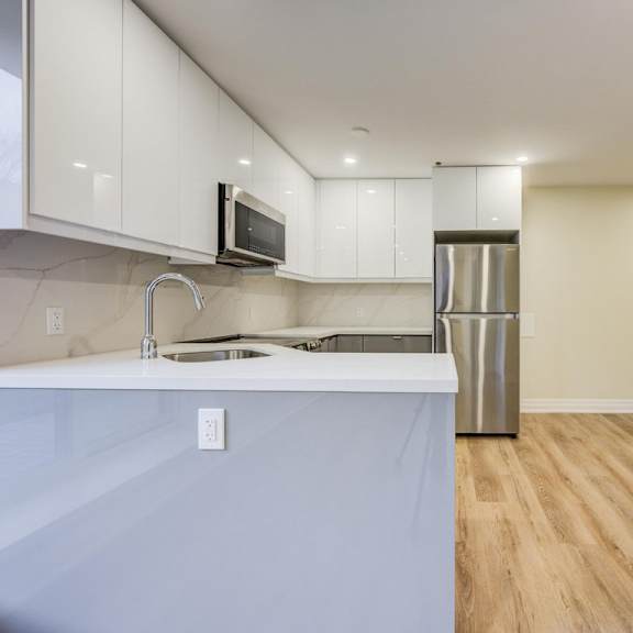 a kitchen with a white counter top and a stainless steel refrigerator.