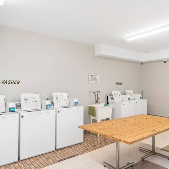 a room with a table in the middle and a wall with a sign that says washer dryer.