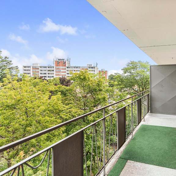 a balcony with a metal railing and a green carpet.