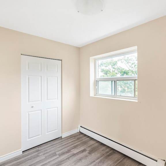 a room with a white door and a window with a view of trees outside.
