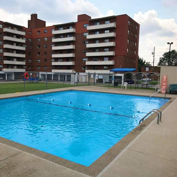 a large swimming pool in front of a red brick apartment building.