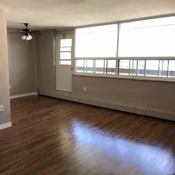 a room with wooden flooring and a window with blinds.