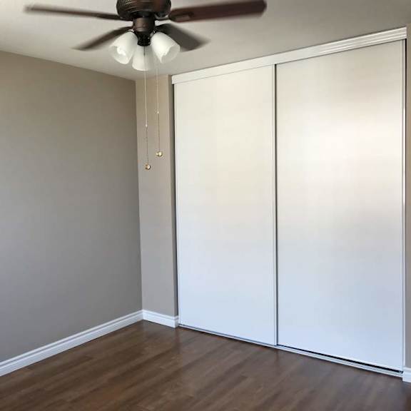 a room with a ceiling fan and a white closet.