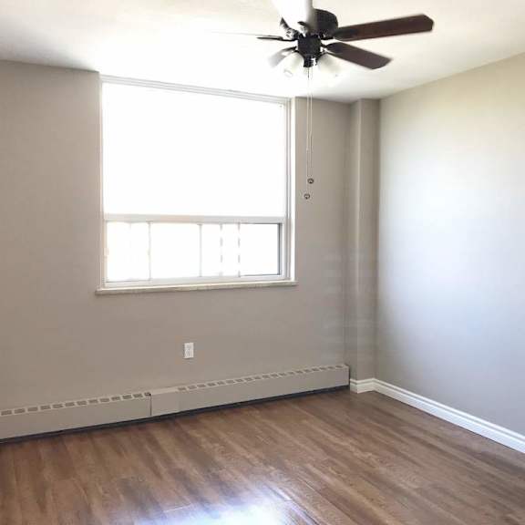 a room with a ceiling fan and a window.
