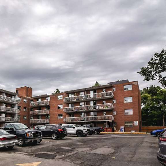 a parking lot with cars and apartment buildings in the background.