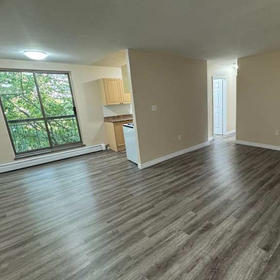 a room with wooden flooring and a window overlooking a tree-filled yard.
