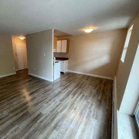 a room with wooden flooring and a white refrigerator.
