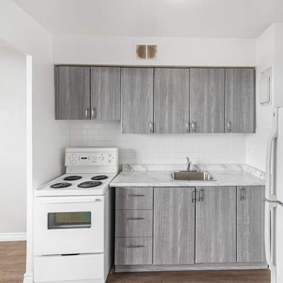 a white stove and sink in a kitchen with grey cabinets.