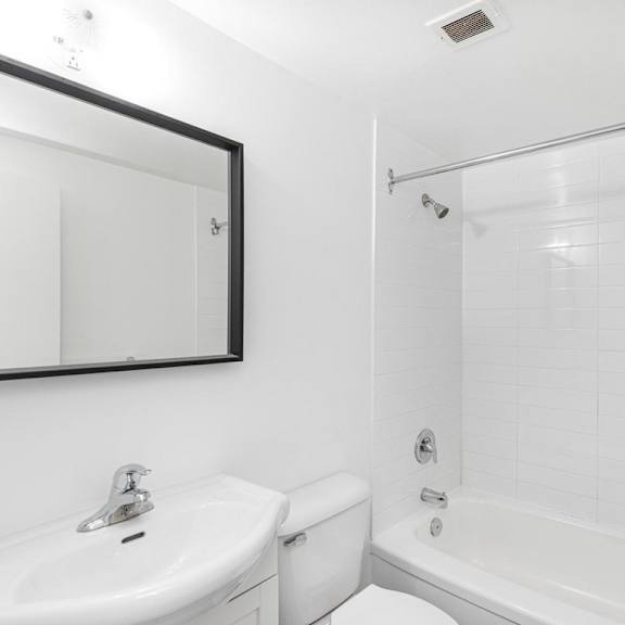 a white bathroom with a sink, toilet, and bathtub.
