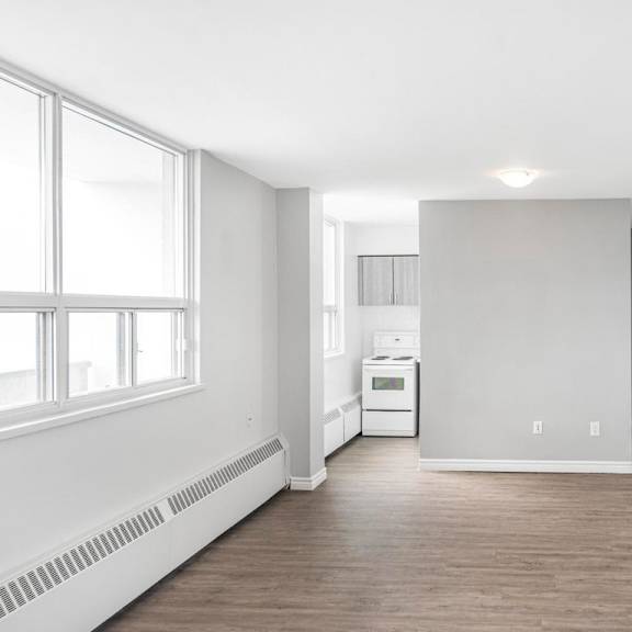 a spacious, empty room with a window on the left and a white appliance in the middle.