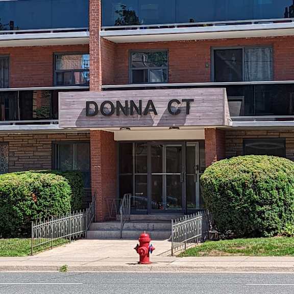 a red fire hydrant is in front of a building named donna court.
