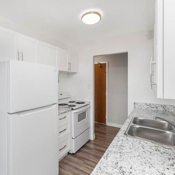 a kitchen with a white refrigerator, stove, and sink.