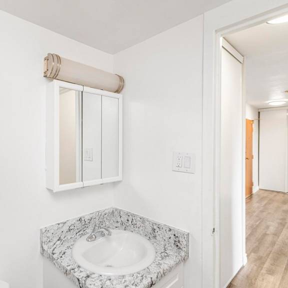 a bathroom with a marble sink and a window with blinds.