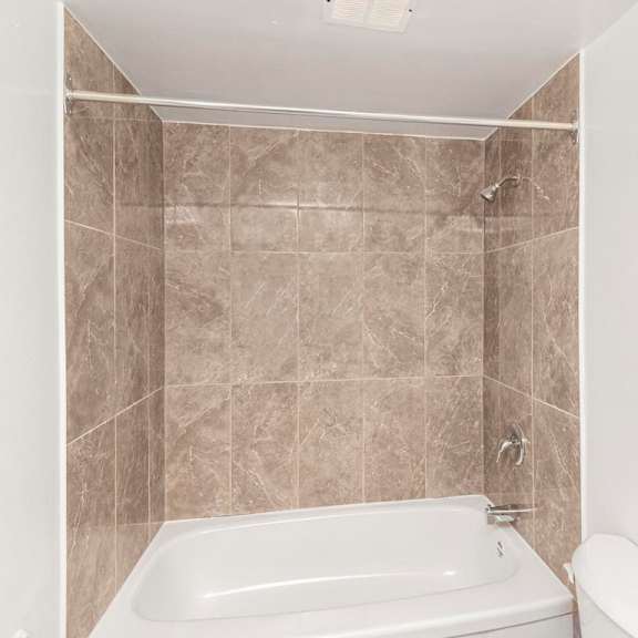 a bathroom with a tiled shower area and a bathtub.