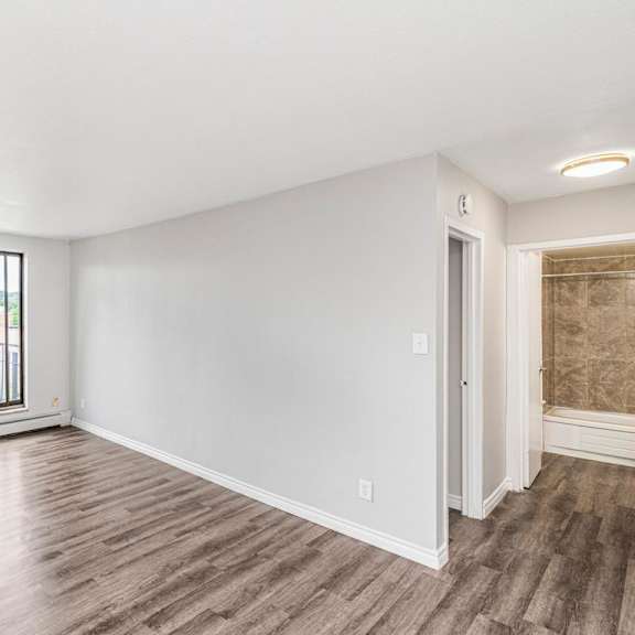a room with a large window and wooden flooring.