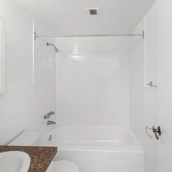 a white bathroom with a tub, sink, and mirror.