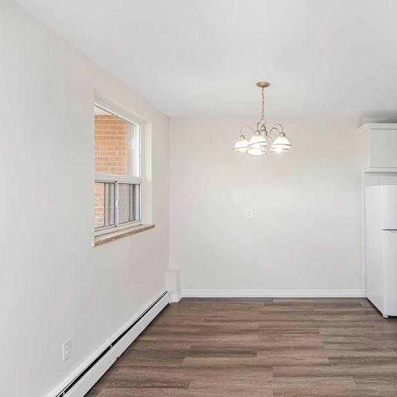 a kitchen with a white refrigerator and wooden flooring.