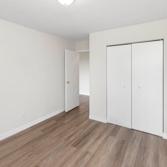 a room with white walls and wood flooring with a white closet.