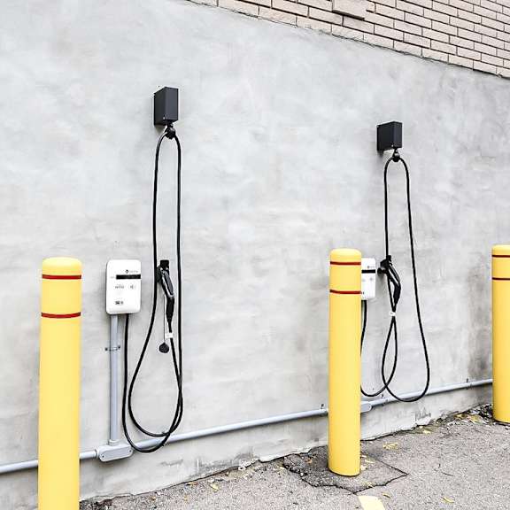 three yellow poles with cables plugged into a wall socket.
