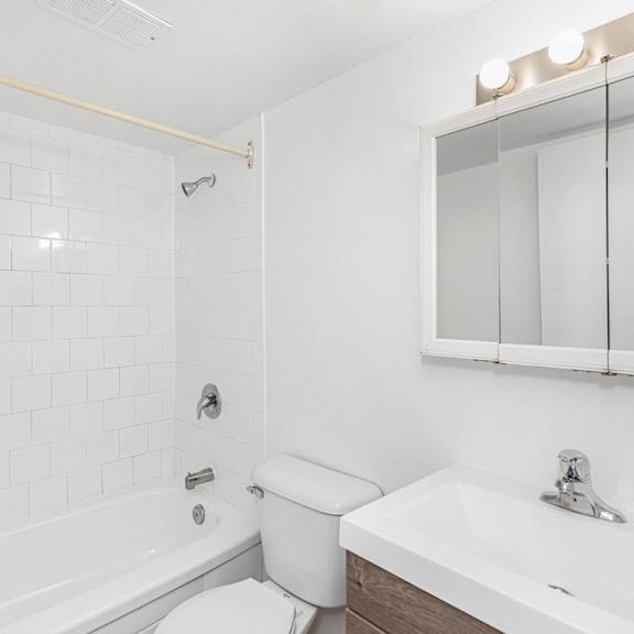 a white bathroom with a toilet, sink, and mirror.