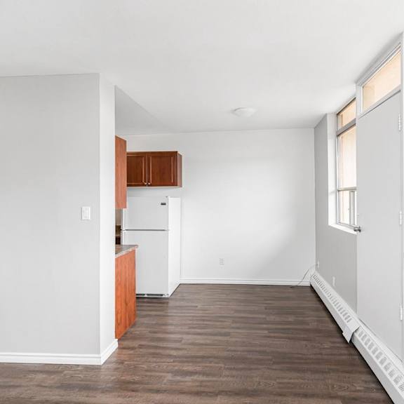 a kitchen with white walls and wooden floors.