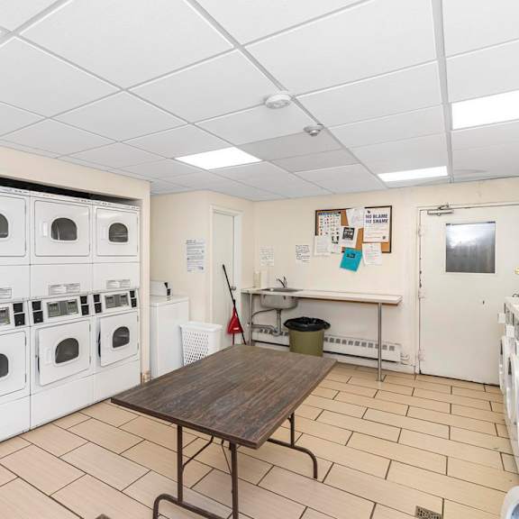 a laundry room with a row of washing machines and a table.