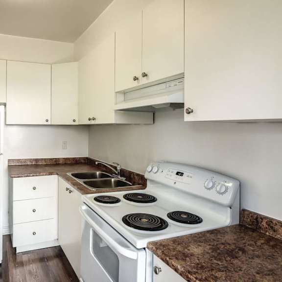 a white refrigerator and stove in a kitchen with white cabinets.