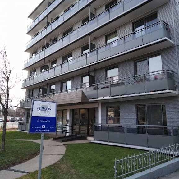 a gibson apartment building with a blue sign in front.