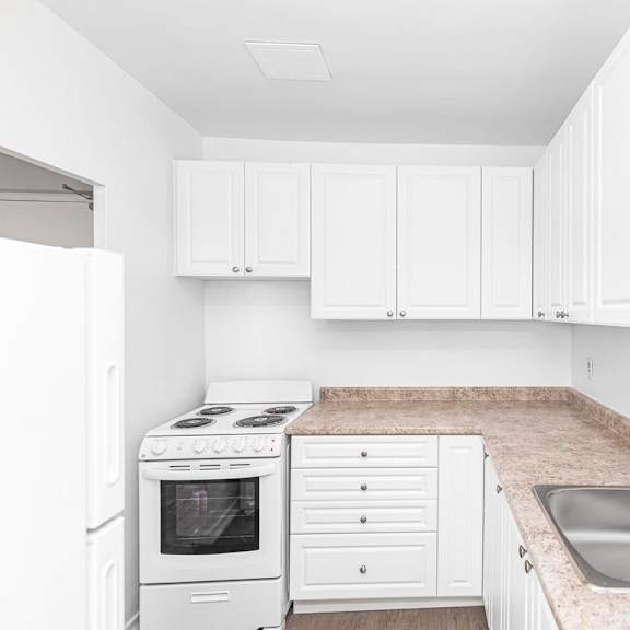 a white kitchen with a sink and a stove.