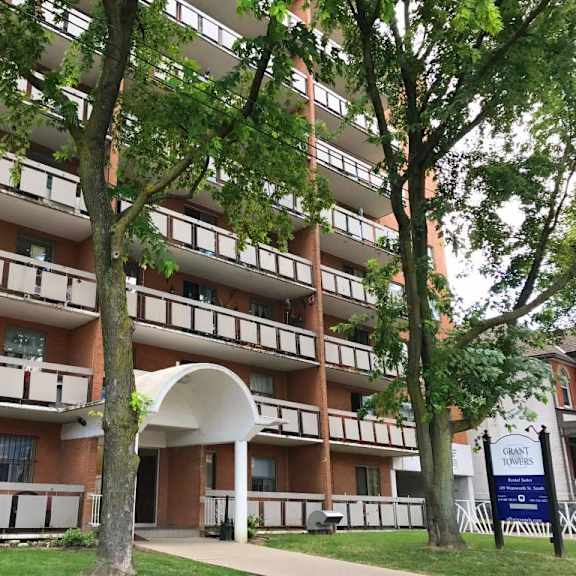 a tall apartment building with balconies and a blue sign in front.
