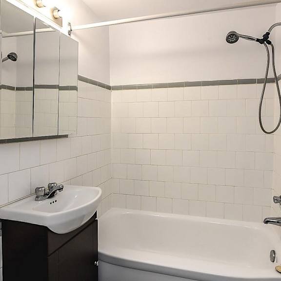 a white tiled bathroom with a sink, toilet, and bathtub.