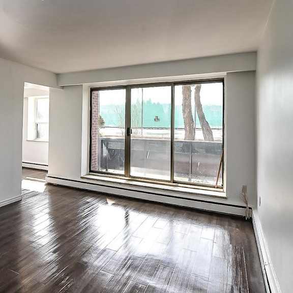 a room with a large window and wooden flooring.