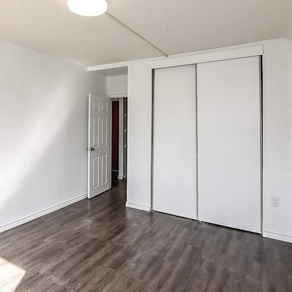 a room with white walls and wood flooring with a door on the right.