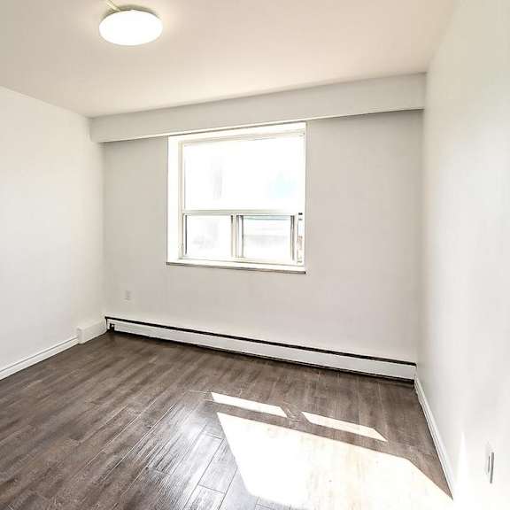 a room with a window and wooden flooring.