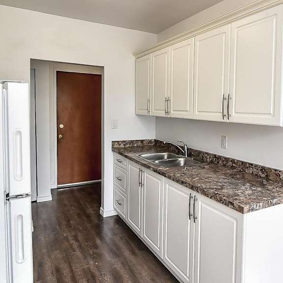 a kitchen with white cabinets and a marble countertop.