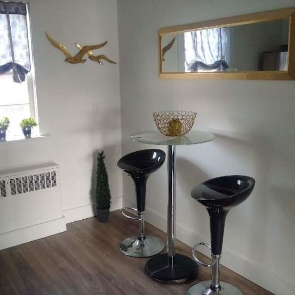 two black bar stools with a white table between them.