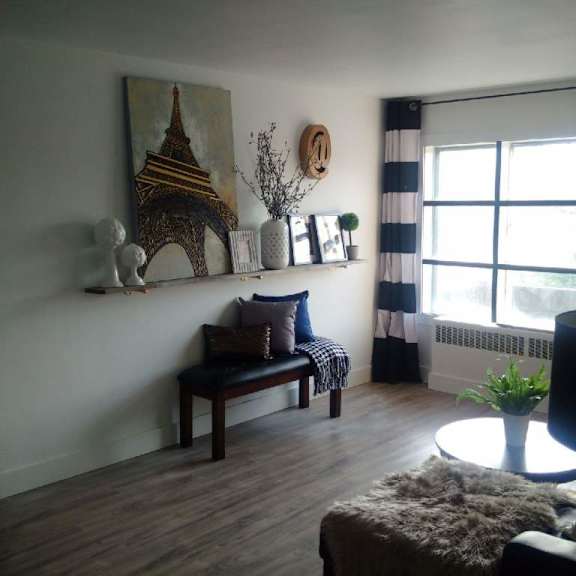 a living room with a wooden bench and a painting of the eiffel tower on the wall.
