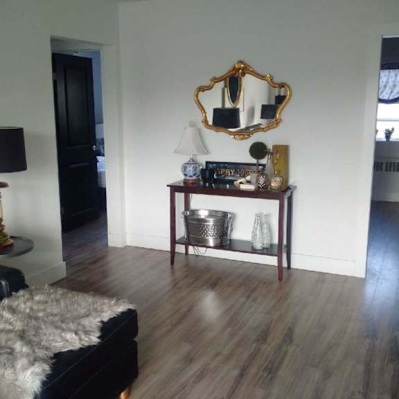 a room with a wooden floor and a mirror above a table with various objects on it.