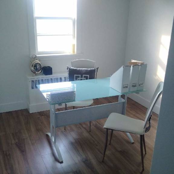 a glass table with a white chair in front of a window.