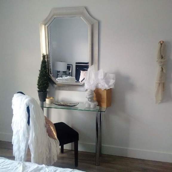 a white chair with a white blanket draped over it sits in front of a mirror.