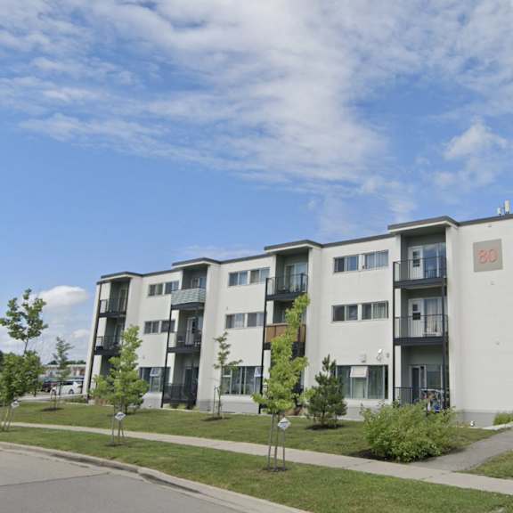 a modern apartment building with balconies and a blue sign in front.
