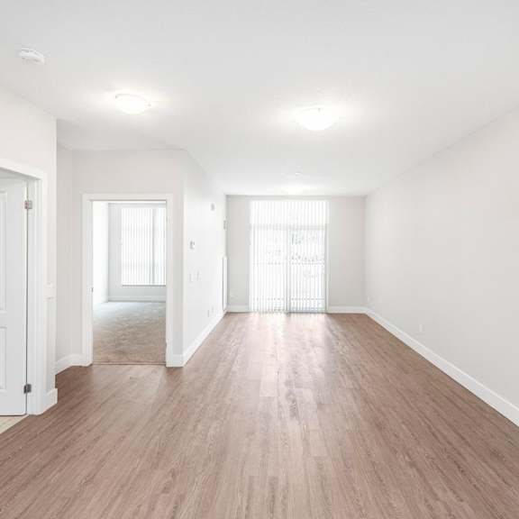 a spacious room with wooden floors and white walls.
