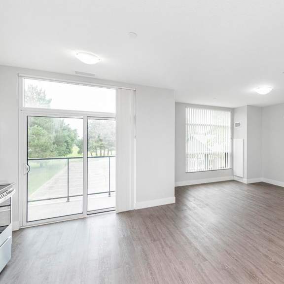 a spacious room with wooden flooring and large windows.