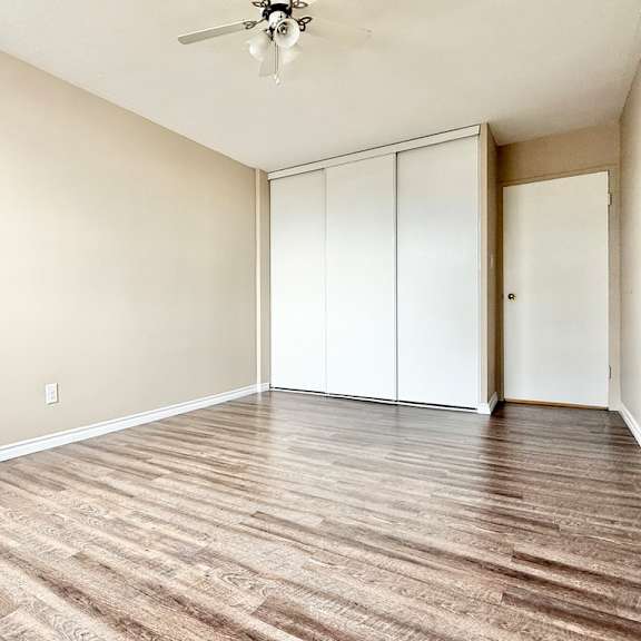 a room with a ceiling fan and wood flooring.